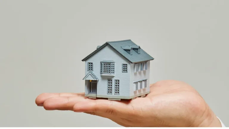 A hand holding a small model house