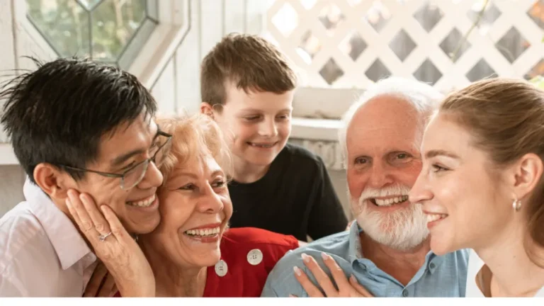 Three generations of a smiling family gathered close together at home