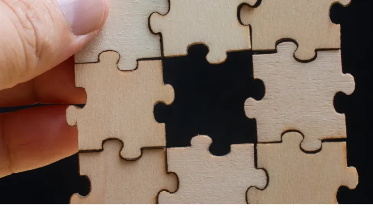 A hand fitting the last wooden puzzle piece into place