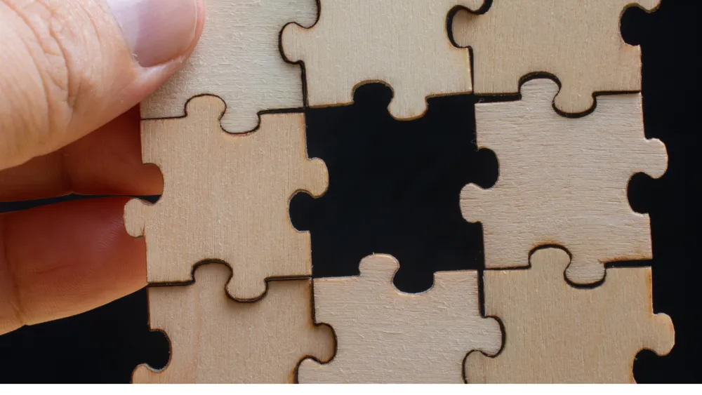 A hand fitting the last wooden puzzle piece into place