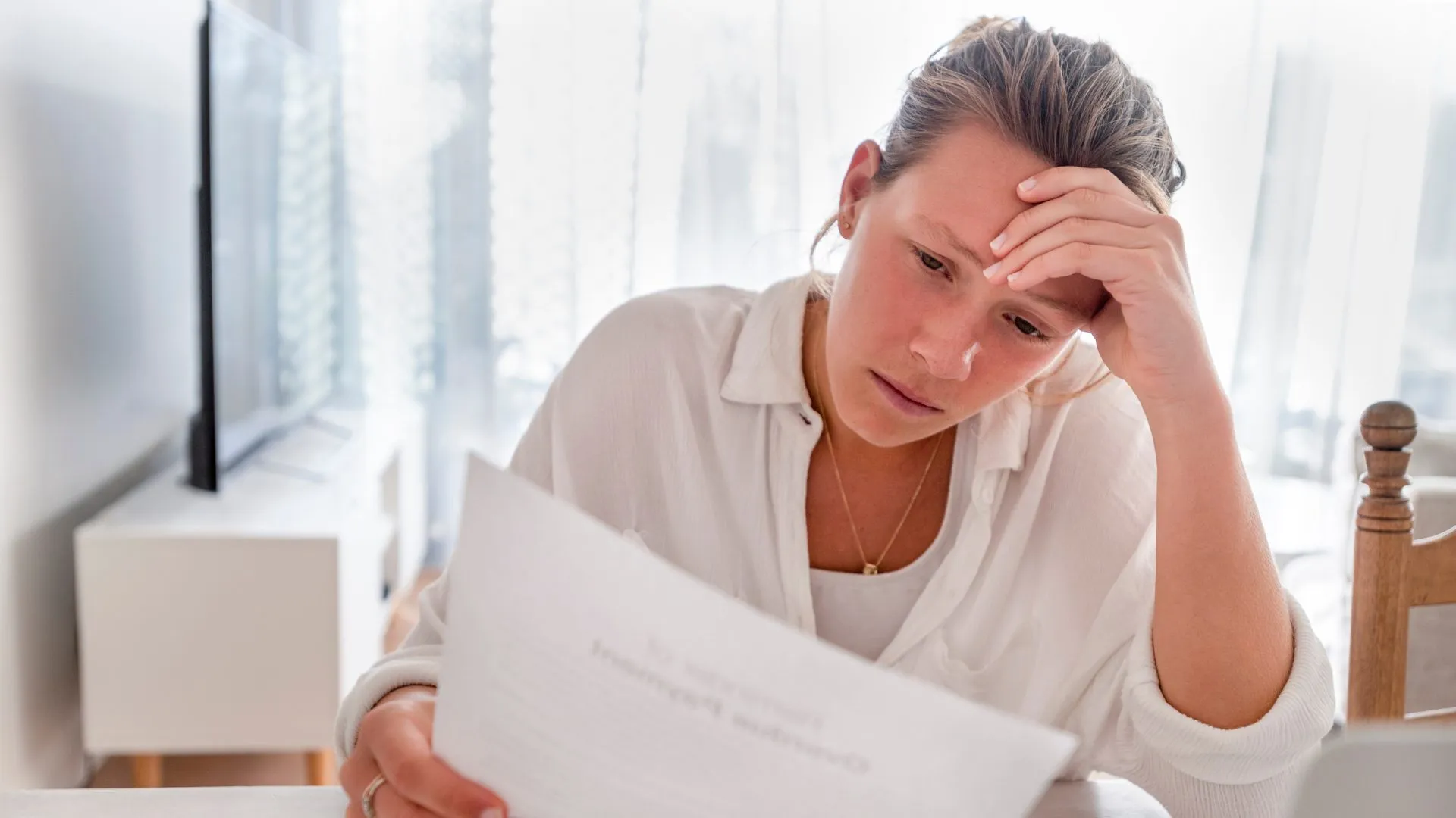 Woman reviewing estate paperwork at her kitchen table, looking overwhelmed