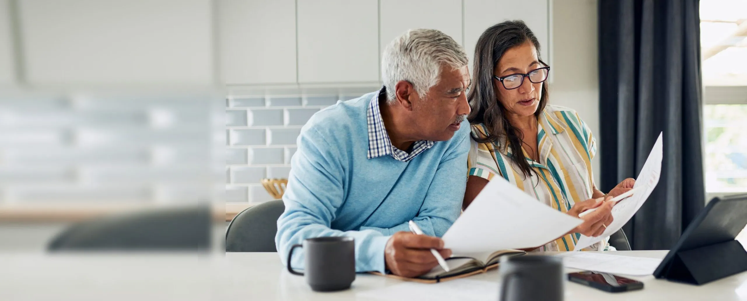 Couple at their kitchen table reviewing paperwork and numbers for their real estate investments